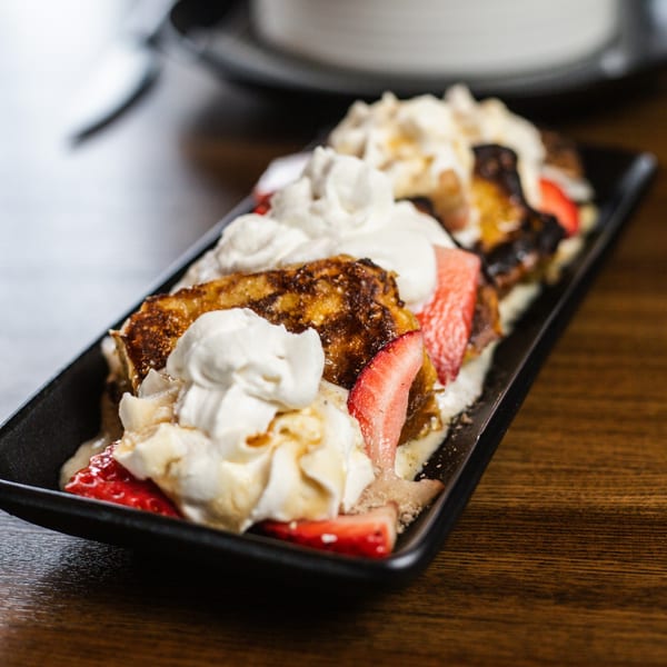Mesa Latin Kitchen's fried plantains topped with whipped cream, strawberries, and a drizzle of sauce.