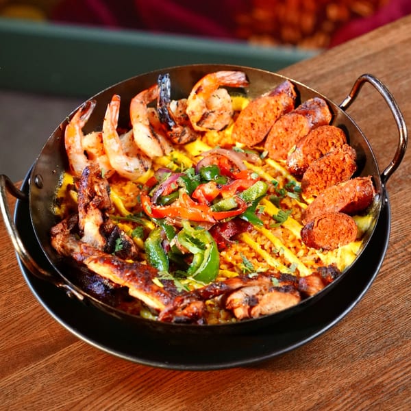 Mesa Latin Kitchen's paella with shrimp, chorizo, chicken, rice, and colorful vegetables in a skillet.