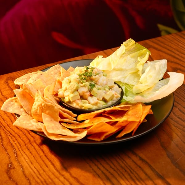 Mesa Latin Kitchen's shrimp and avocado ceviche with tortilla chips and lettuce wraps on a wooden table.
