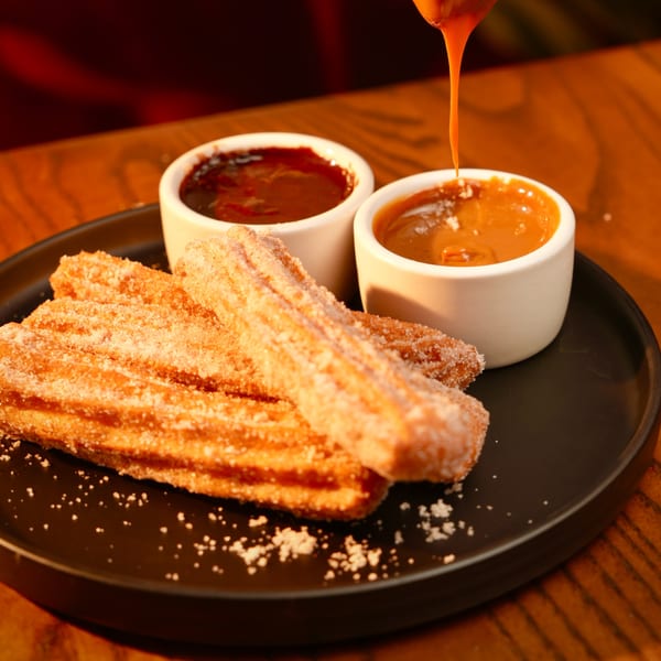Golden churros dusted with sugar and cinnamon, served with chocolate and dulce de leche dipping sauces.